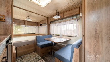 Příjemná venkovská zahrada s rekreačním karavanem a terasou.